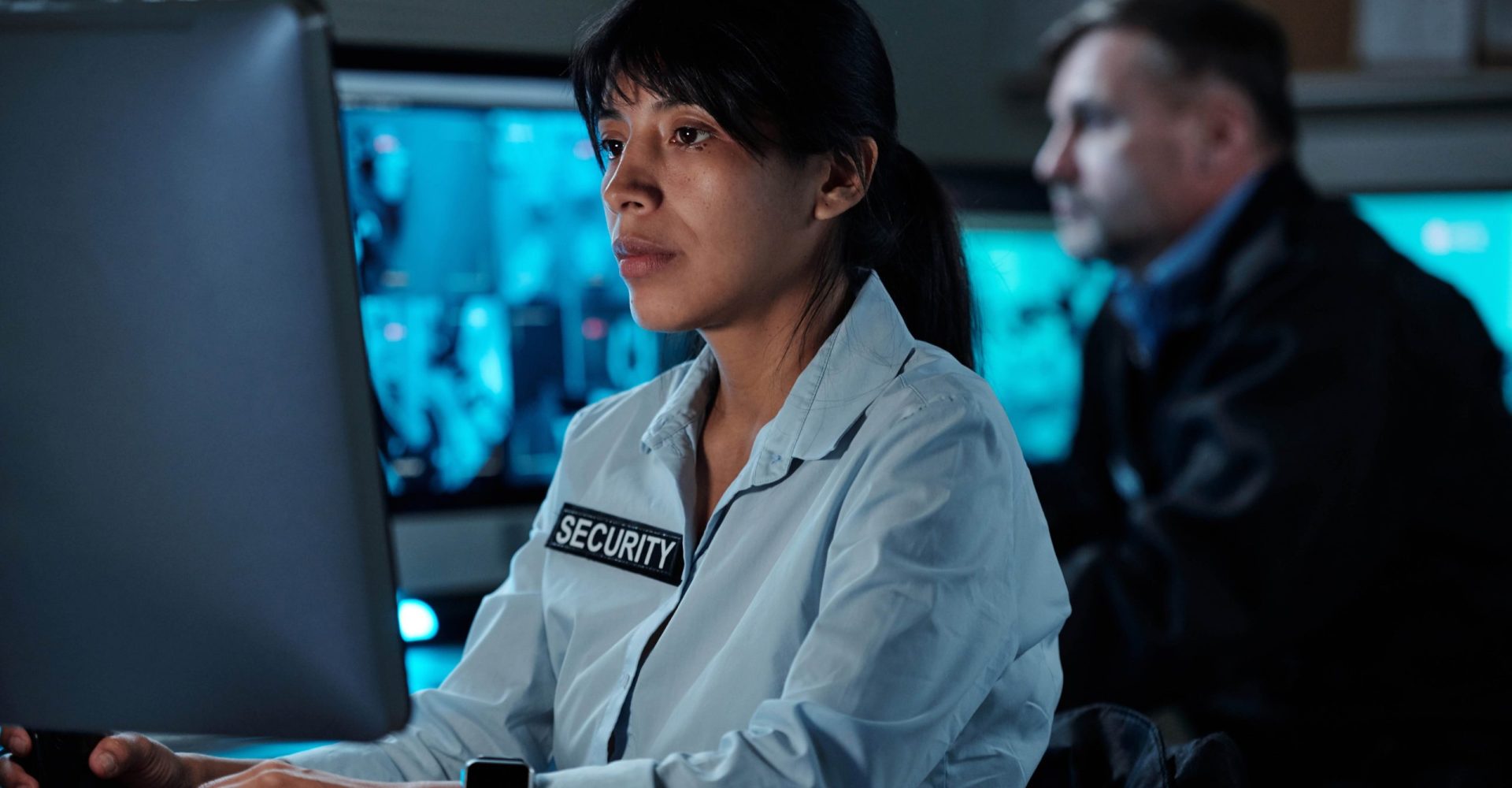 A woman in a white shirt sits at a computer, focused on her work in a well-lit office environment.